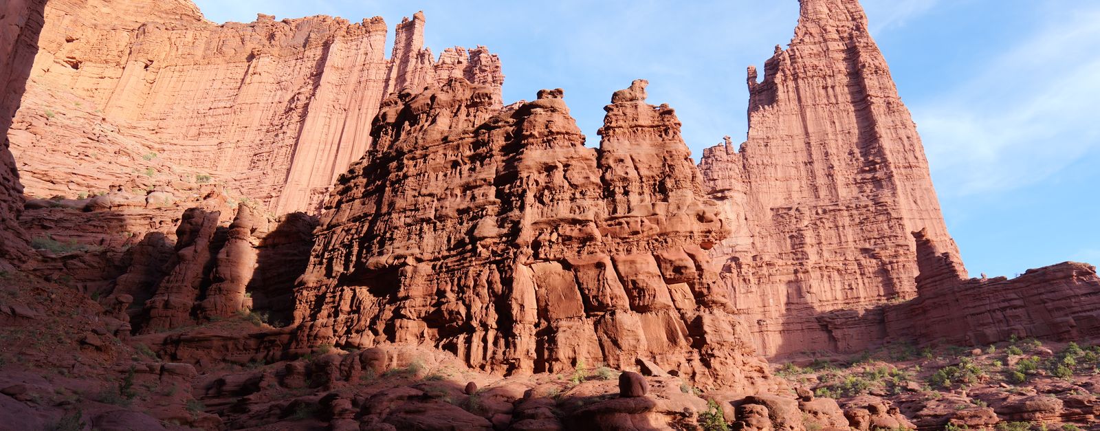 The red sandstone spires of Fisher Towers near Moab, Utah, lit by low sun under a blue sky